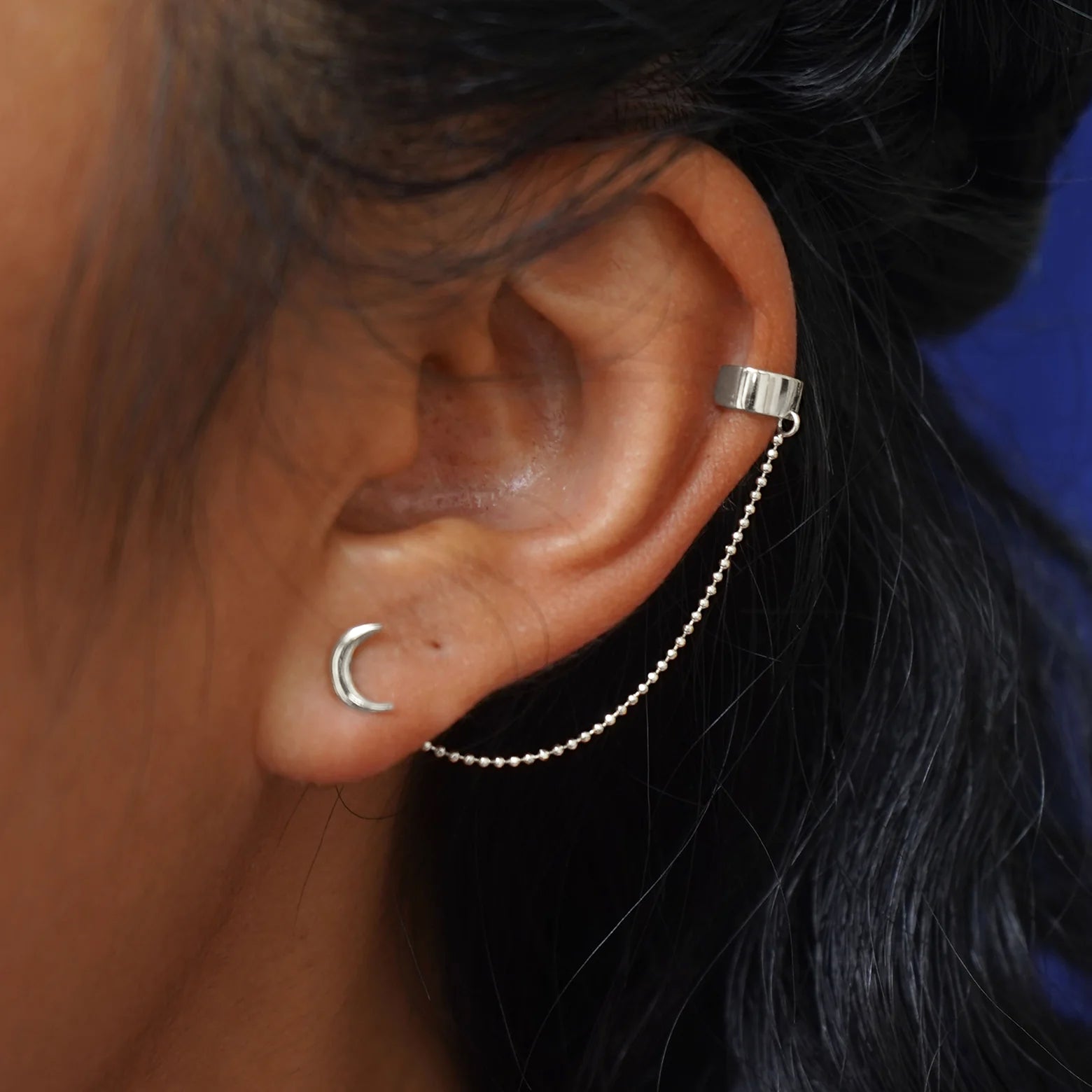 A model's ear wearing a white
 gold Thick Cuff With Chain and a Moon Earring