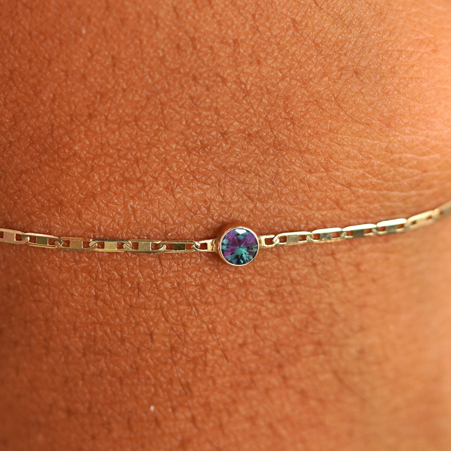 Close up view of a models wrist wearing 14k yellow gold Alexandrite Bracelet