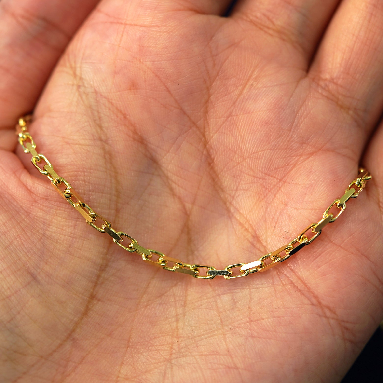 A yellow gold Anchor Chain draped on a model's palm