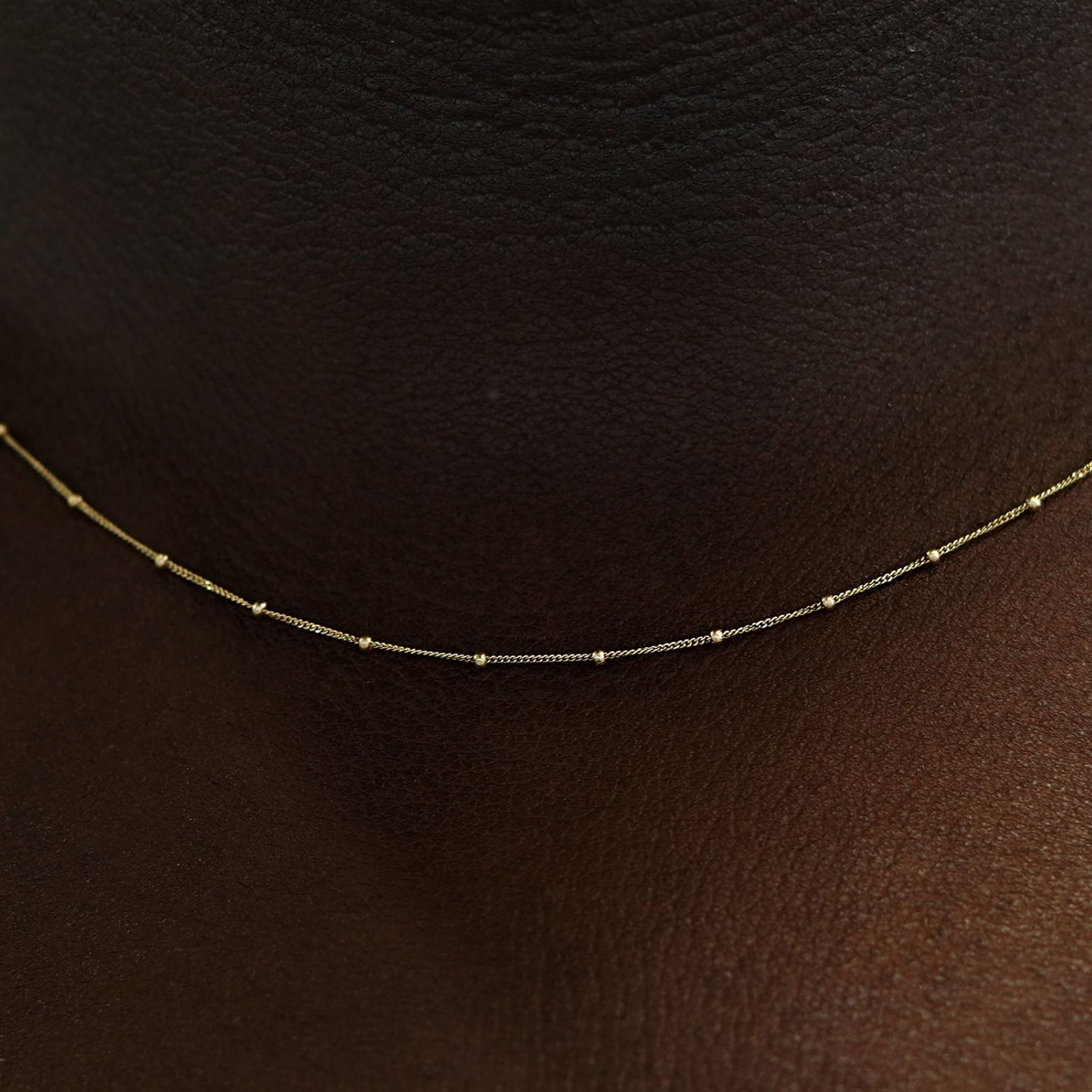 Close up view of a model's neck wearing a yellow gold Beaded Essential Chain