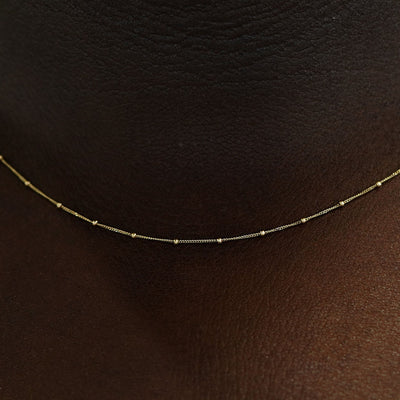 Close up view of a model's neck wearing a yellow gold Beaded Essential Chain