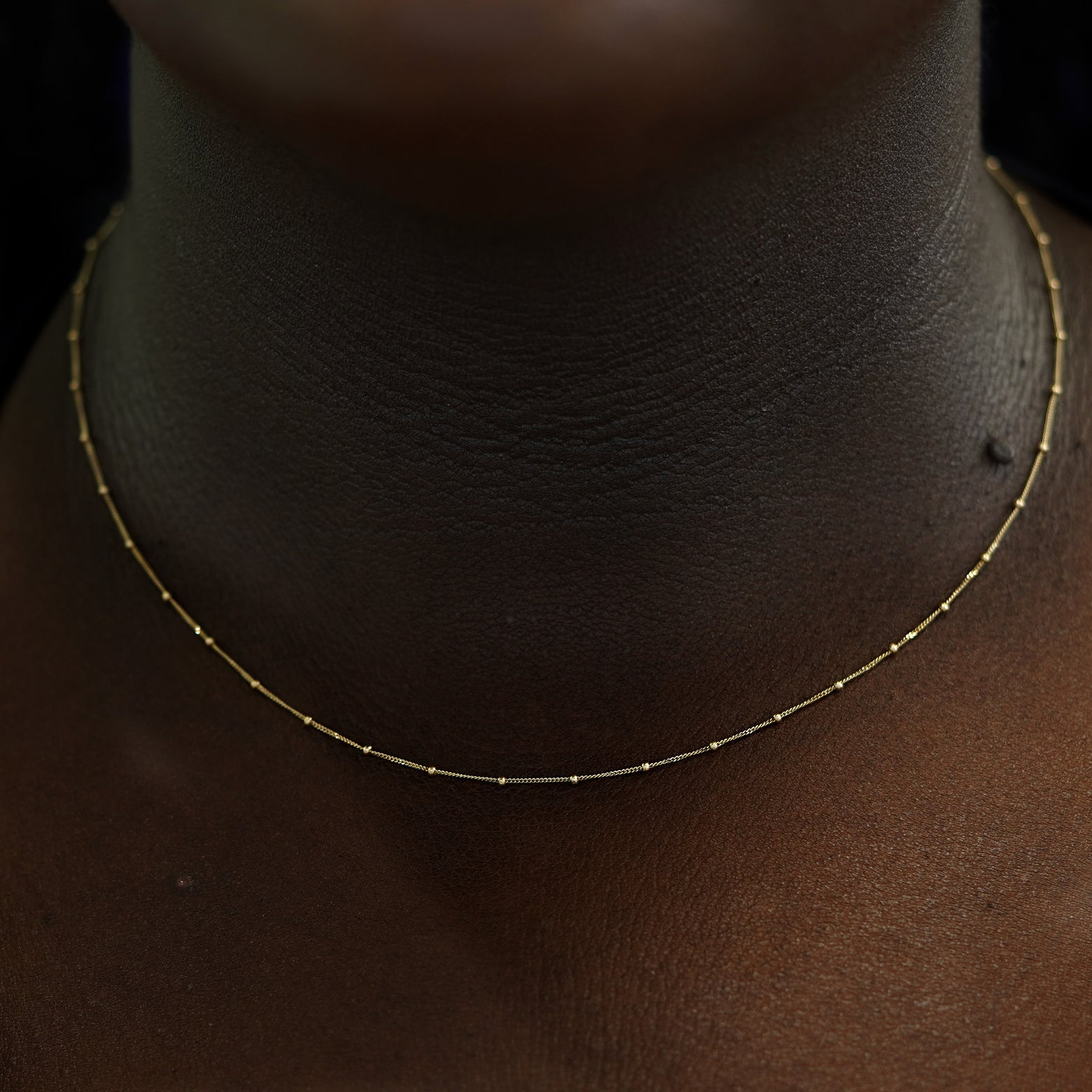 A model's neck wearing a yellow gold Beaded Essential Chain