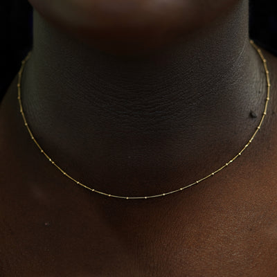 A model's neck wearing a yellow gold Beaded Essential Chain