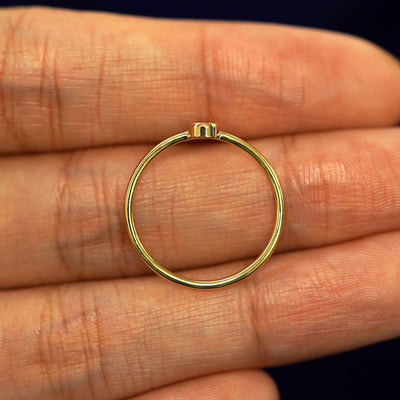 A yellow gold Fire Opal Ring in a model's palm showing the thickness of the band