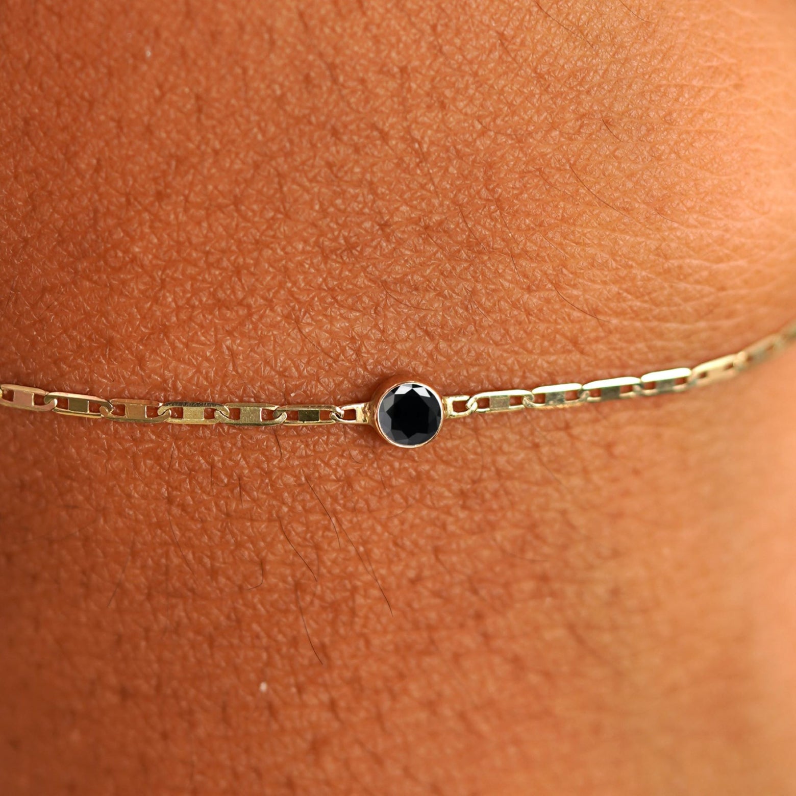 Close up view of a models wrist wearing 14k yellow gold Black Diamond Bracelet