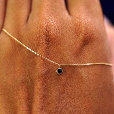 A solid yellow gold Black Diamond Necklace draped across the back of a model's hand