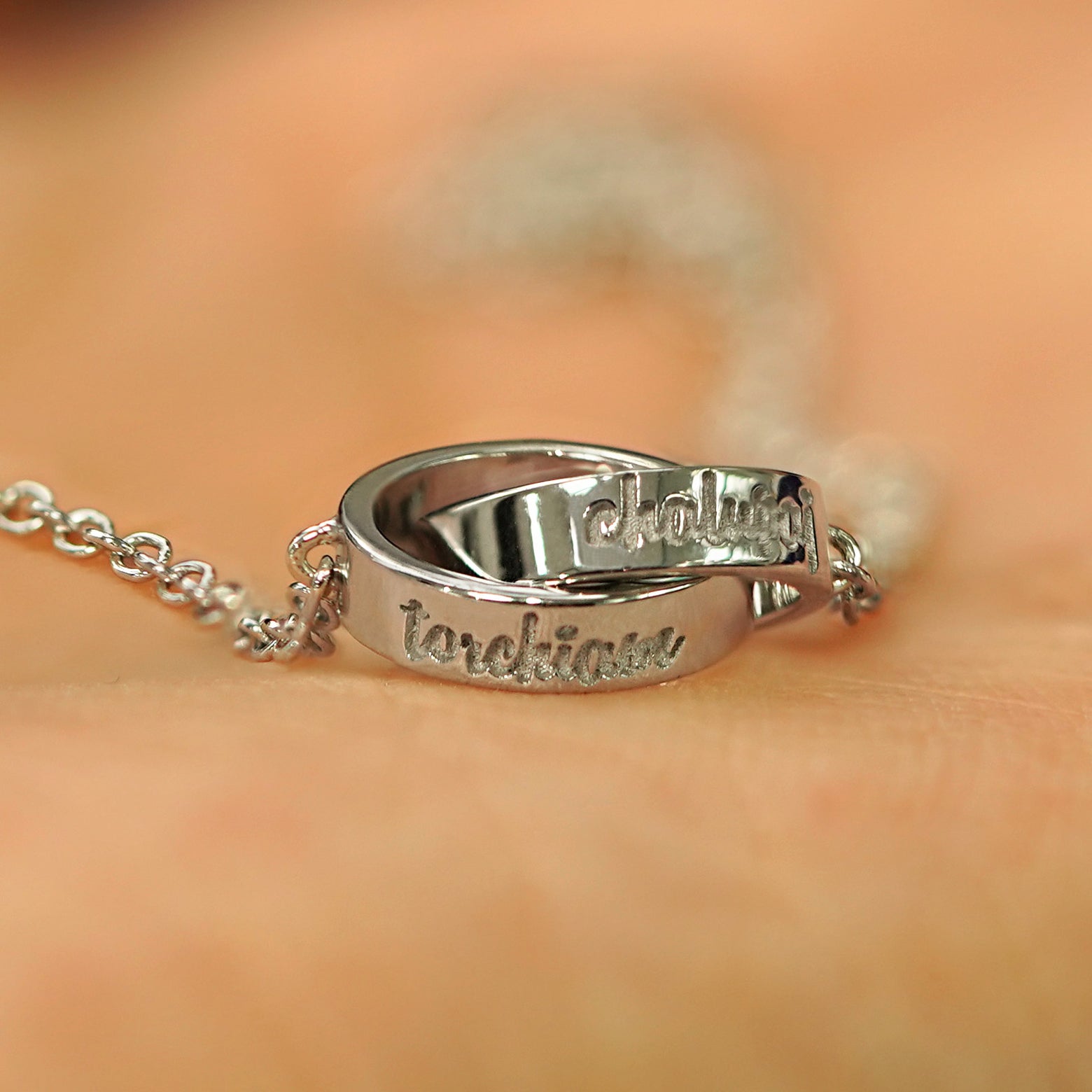 A solid white gold Bound Together Bracelet showing engraved names on the outside of both rings