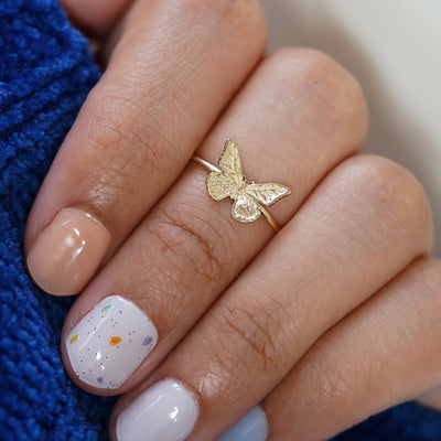 Close up view of a hand gripping a sweater wearing a Butterfly Ring as a midi ring