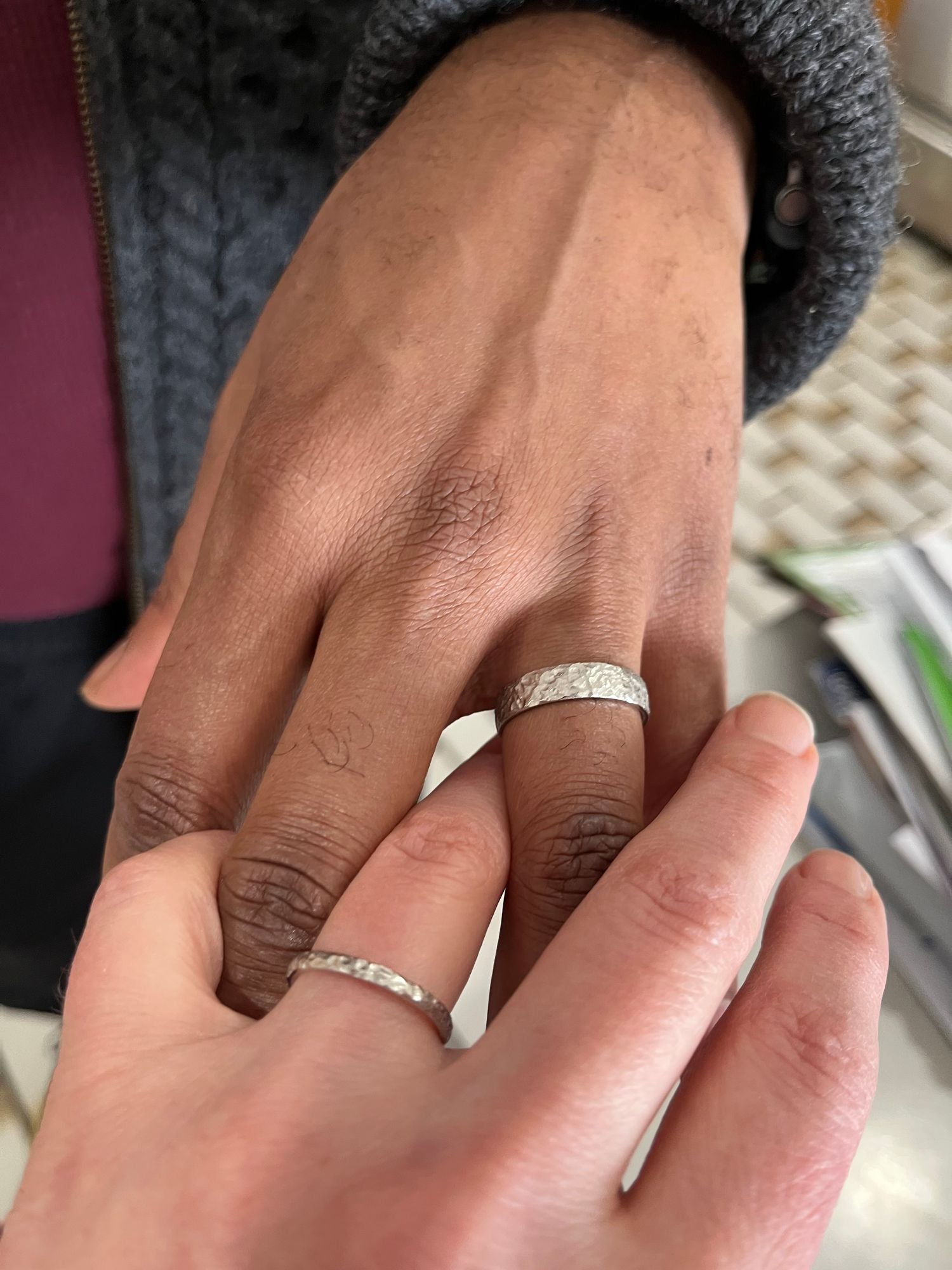 Two customers showing off their white gold hammered wedding bands