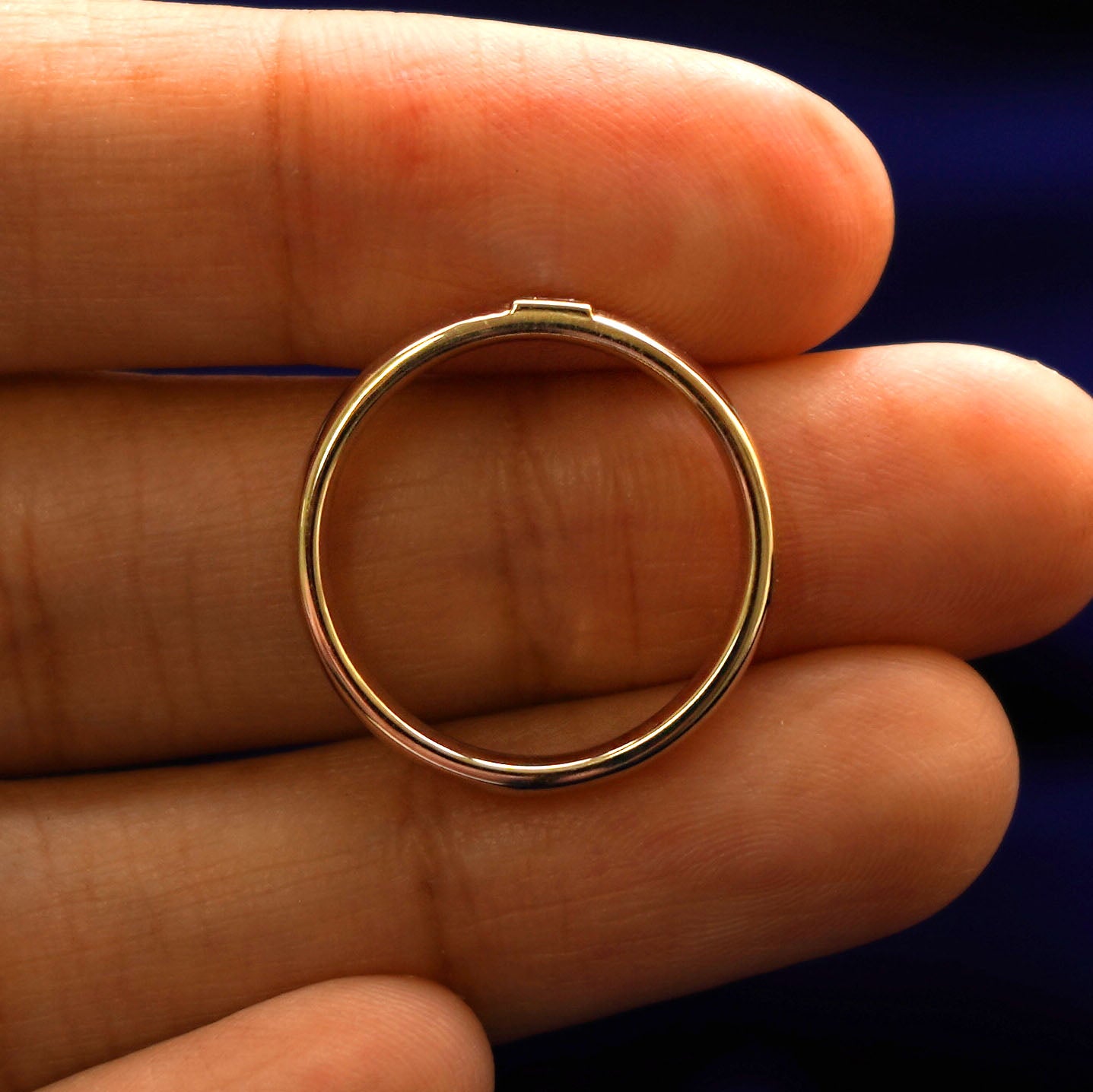 A yellow gold Square Carre Cut Diamond Band in a model's hand showing the thickness of the band