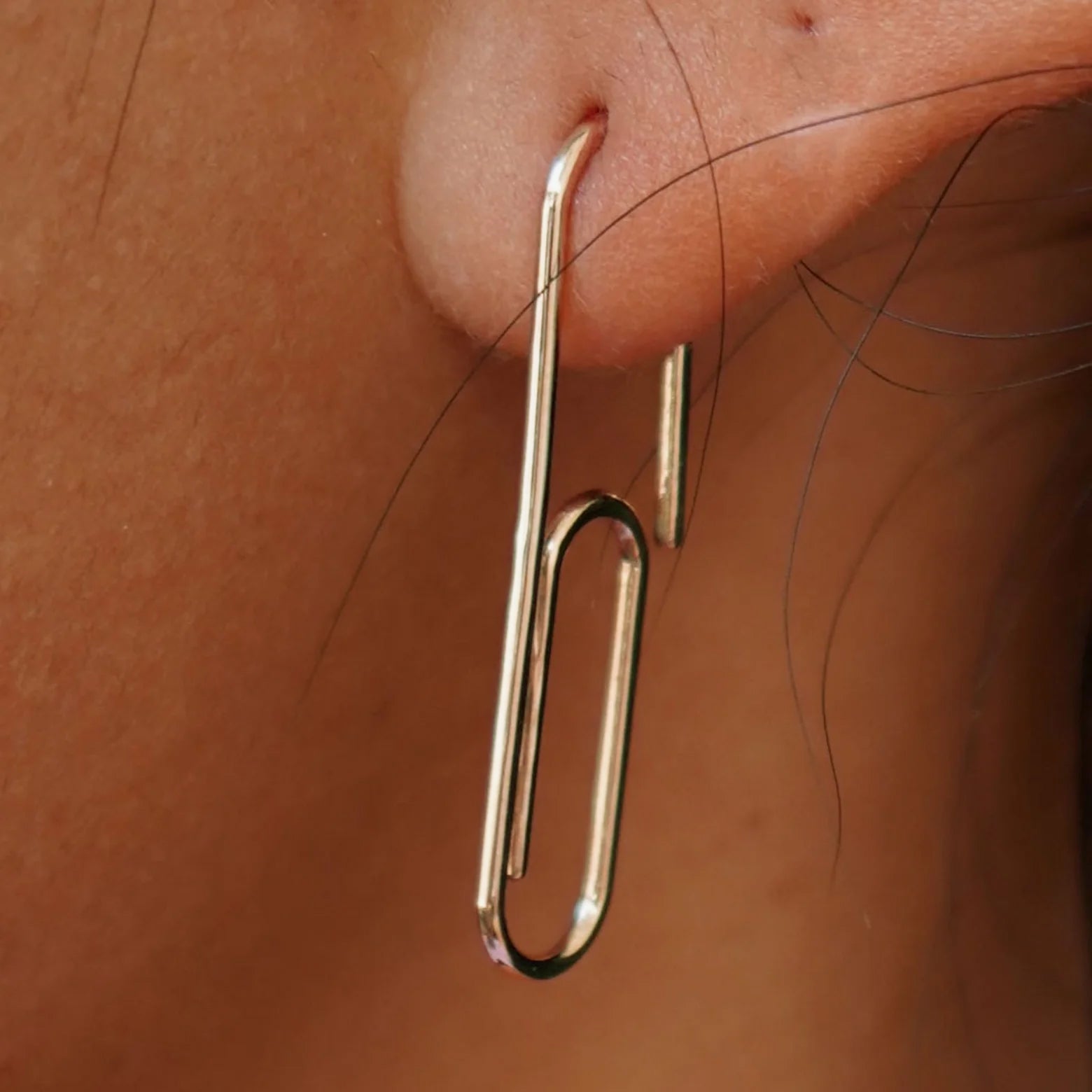 Close up view of a model's ear wearing a Champagne gold Not A Paper Clip Earring