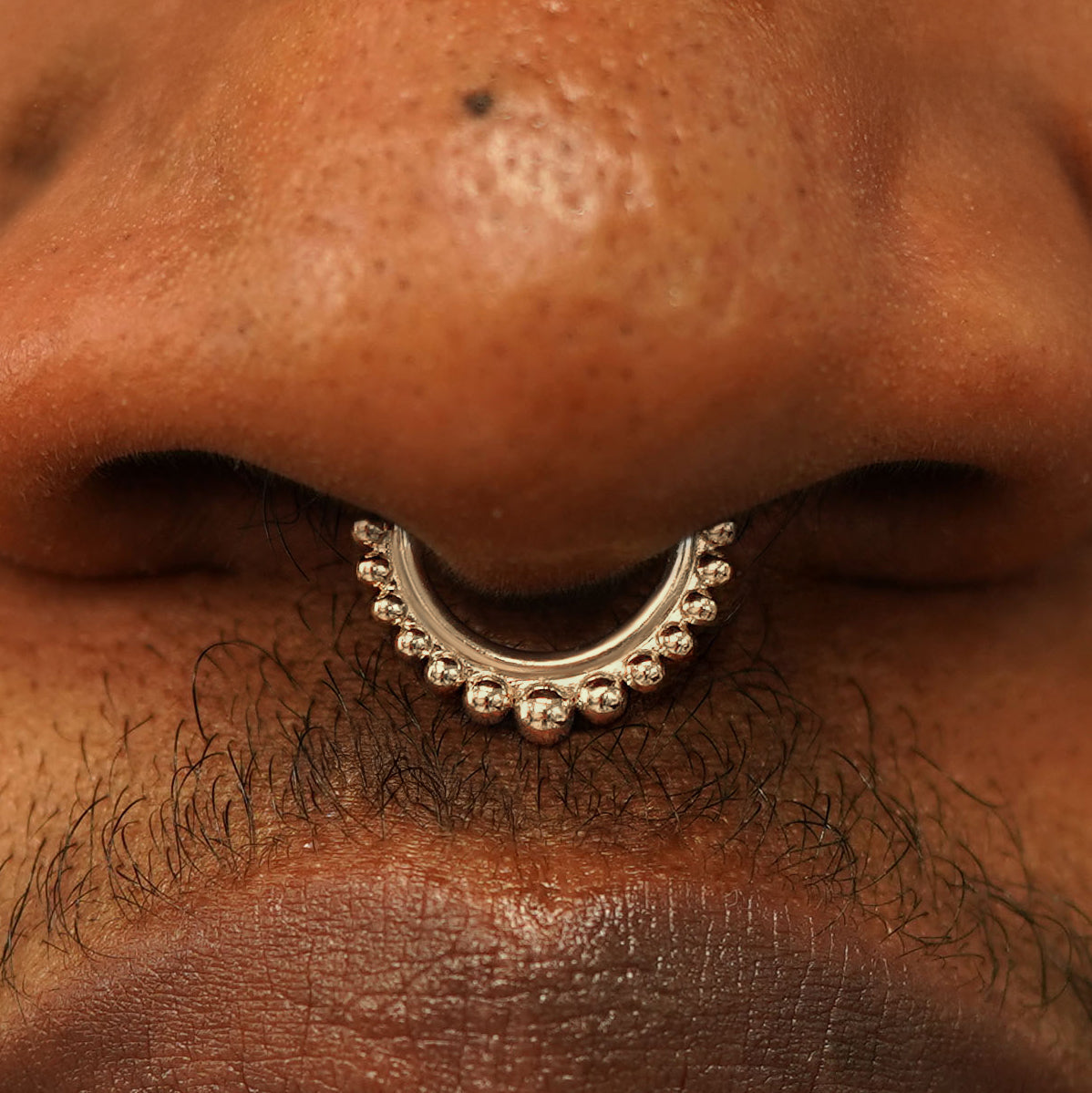 Close up view of a model's nose wearing a 14k champagne gold Beaded Septum