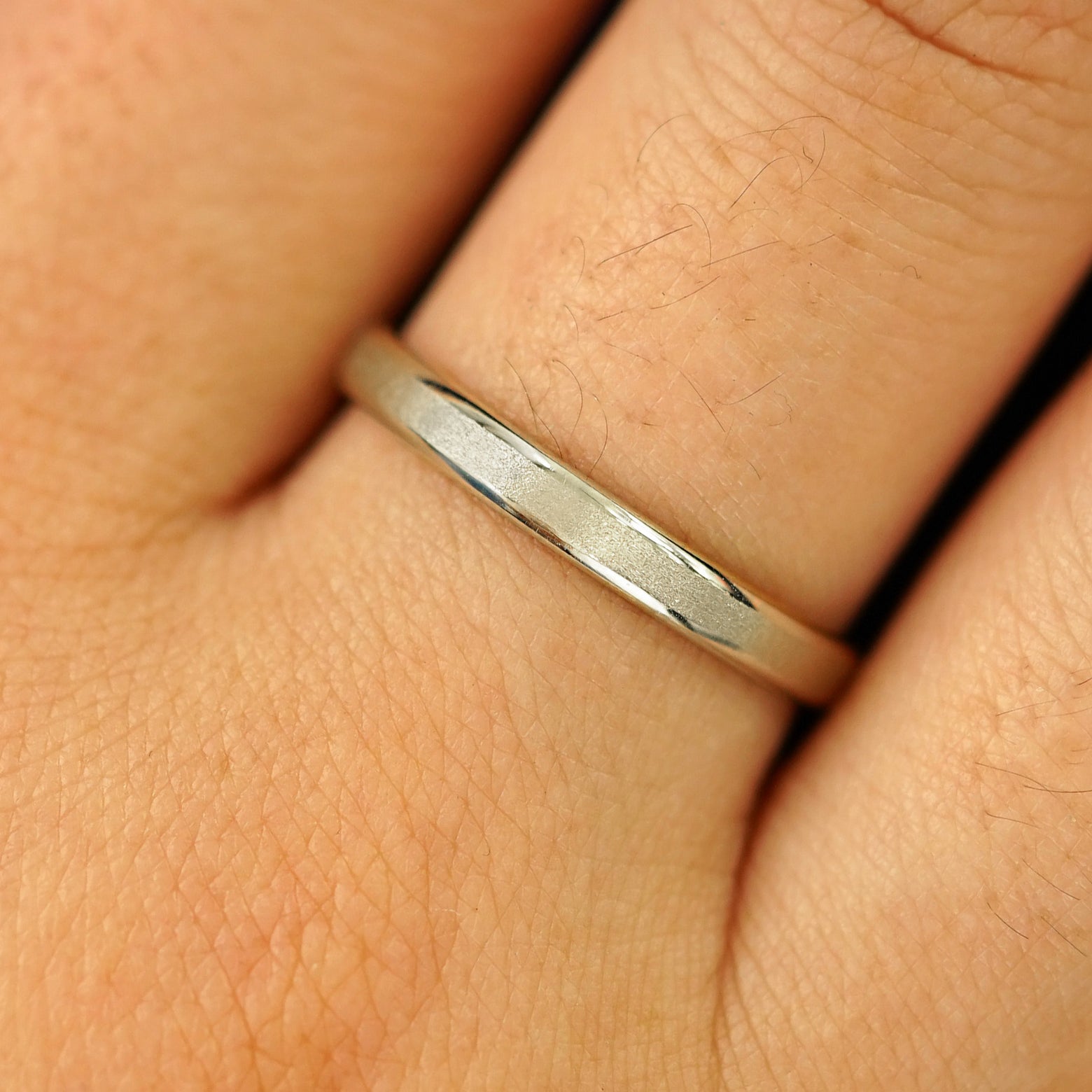 Close up view of a model's hand wearing a solid champagne gold Beveled Edge Band