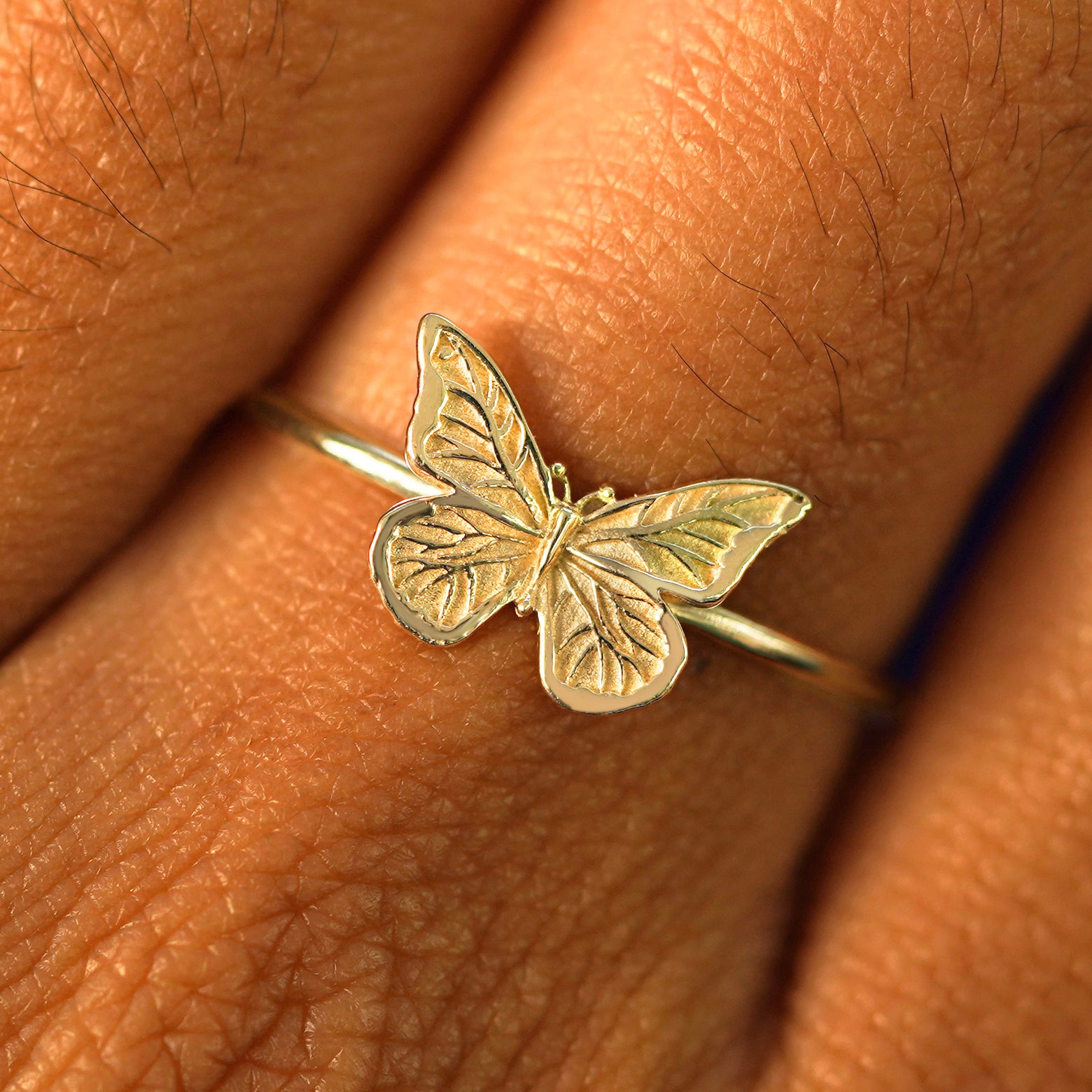 Close up view of a model's fingers wearing a champagne gold Butterfly Ring