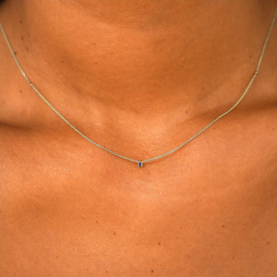 Close up view of a model's neck wearing a solid 14k champagne gold Gemstone Cable Necklace in sapphire
