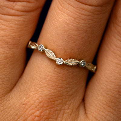 Close up view of a model's fingers wearing a 14k champagne gold Chevron Leaves and Round Diamonds Band