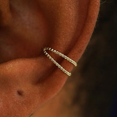 Close up view of a model's ear wearing a 14k Champagne gold Bead Ear Cuff