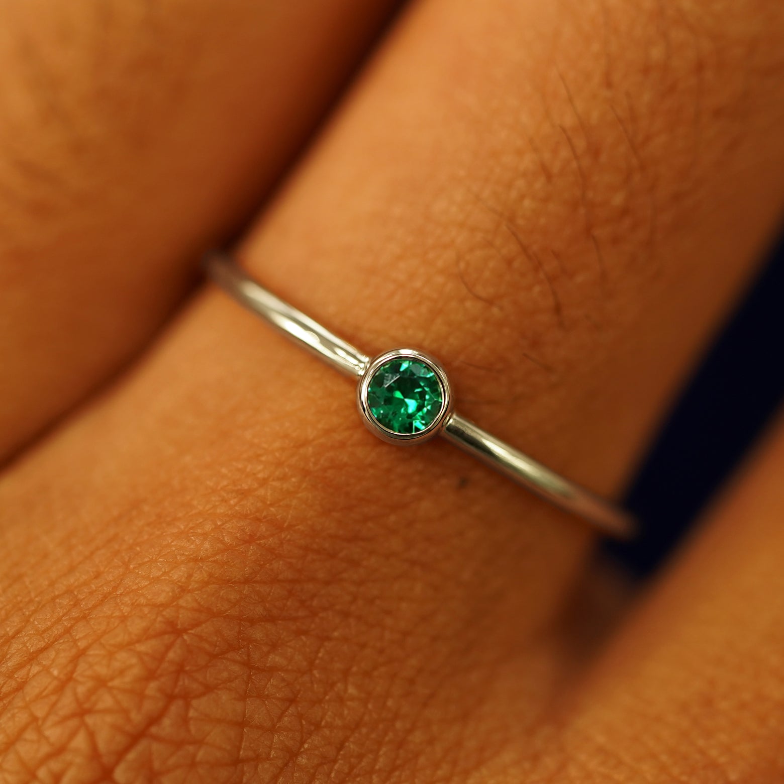 Close up view of a model's fingers wearing a 14k champagne gold Emerald Ring