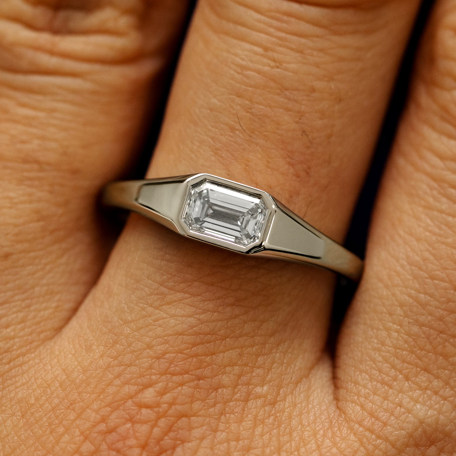 Close up view of a model's fingers wearing a 14k champagne gold Emerald Cut Lab Created Diamond Signet Ring