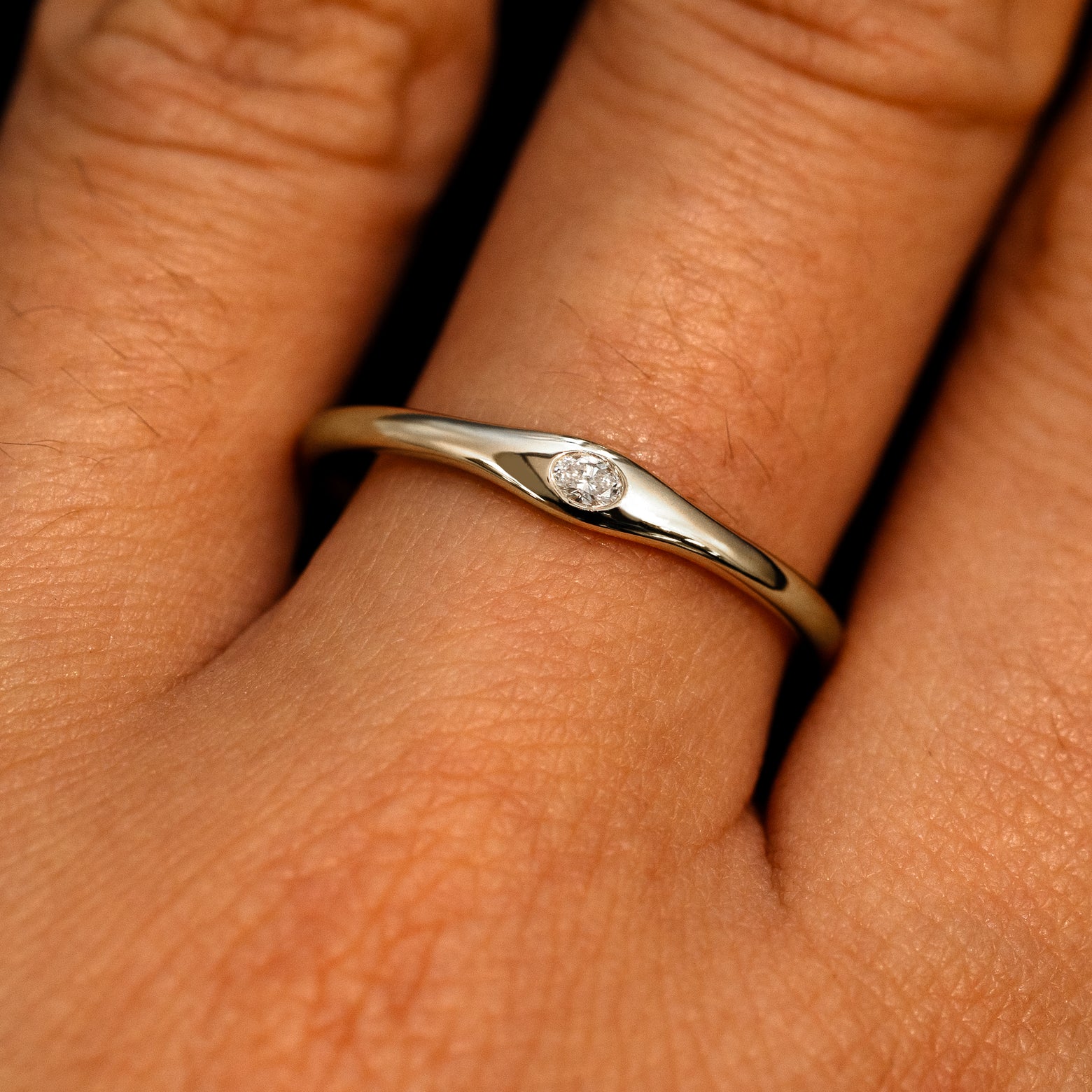 A 14k champagne gold Flush Set Oval Diamond Ring on a model's finger