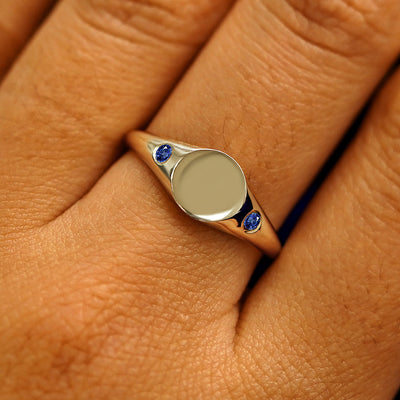 Close up view of a model's fingers wearing a 14k champagne gold Gemstone Signet Ring in sapphire