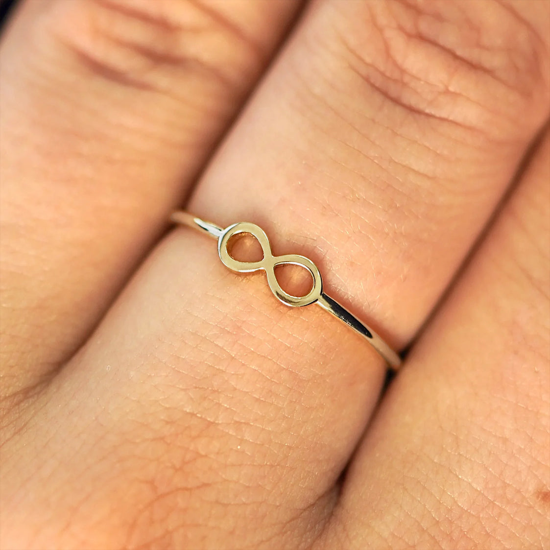 Close up view of a model's fingers wearing a 14k champagne gold Infinity Ring