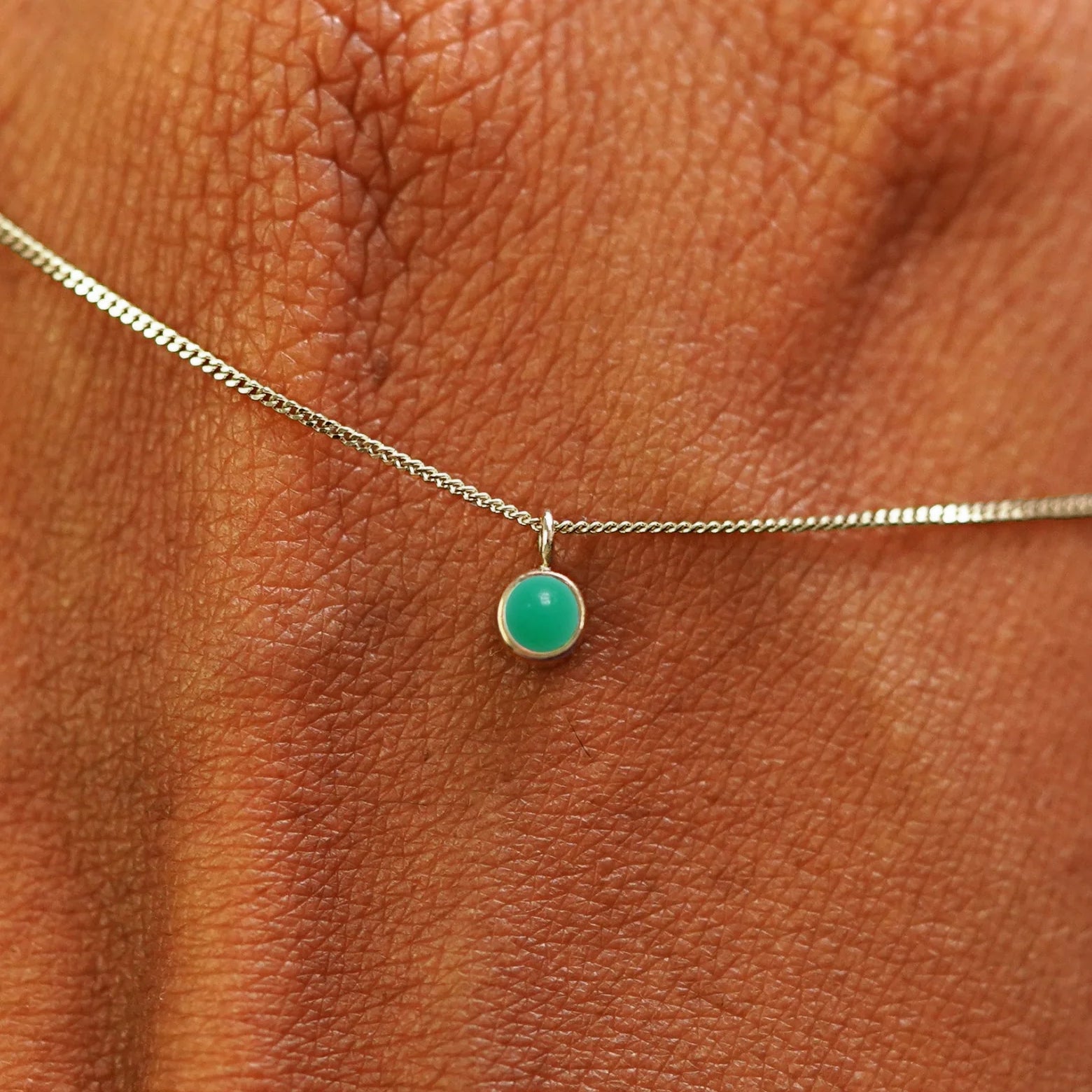 Close up view of a 14k champagne gold Jade Necklace draped across the back of a model's hand