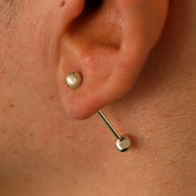 Close up view of a model's ear wearing a 14k champagne gold Large Straight Barbell through a lobe piercing