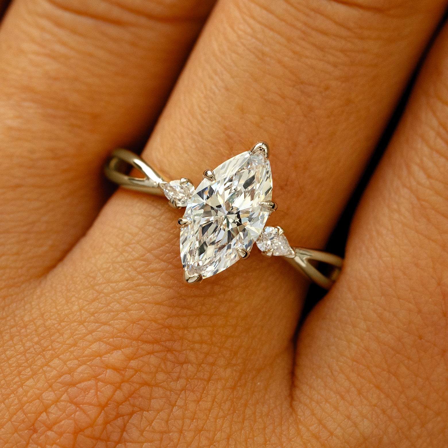 A solid 14k champagne gold Marquise Lab Diamond Three Stone Ring on a model's finger