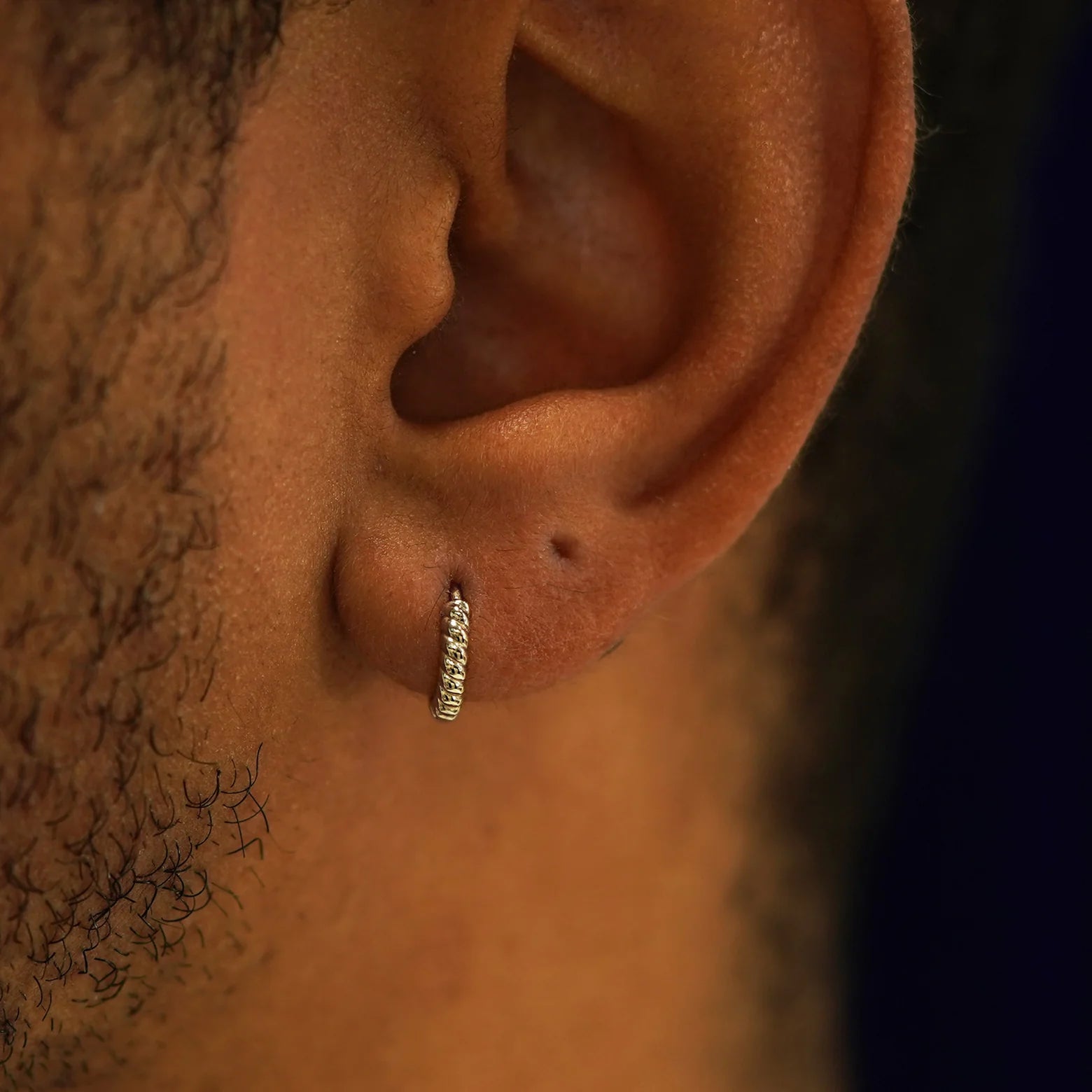 A model's ear wearing a 14k champagne gold Mini Rope Huggie Hoop Earring