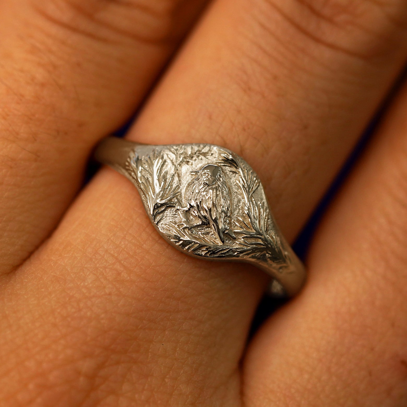 Close up view of a model's fingers wearing a 14k champagne gold Pine and Bird Signet Ring