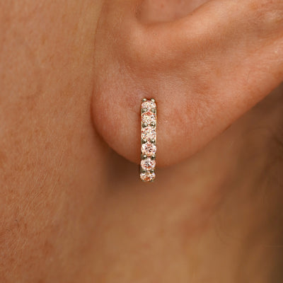 Close up view of a model's ear wearing a champagne gold Small Pink Lab Diamond Huggie Hoop