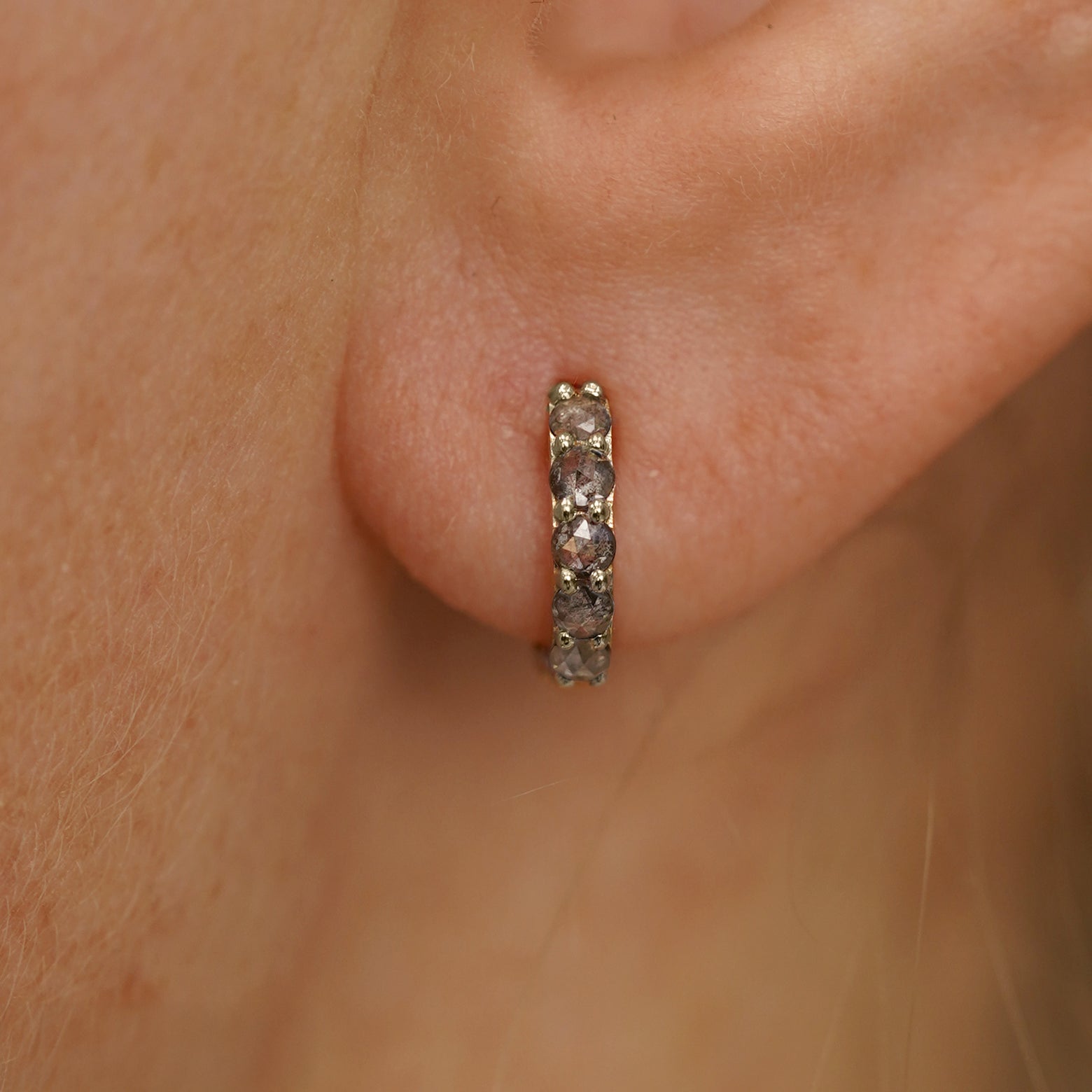 Close up view of a model's ear wearing a champagne gold Mini Salt and Pepper Diamond Huggie Hoop