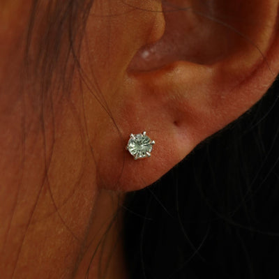 Close up view of a model's ear wearing a champagne gold 4mm Montana Teal Sapphire Earring