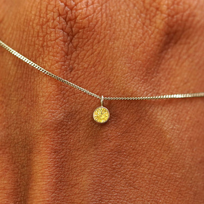 Close up view of a 14k champagne gold Yellow Diamond Necklace draped across the back of a model's hand