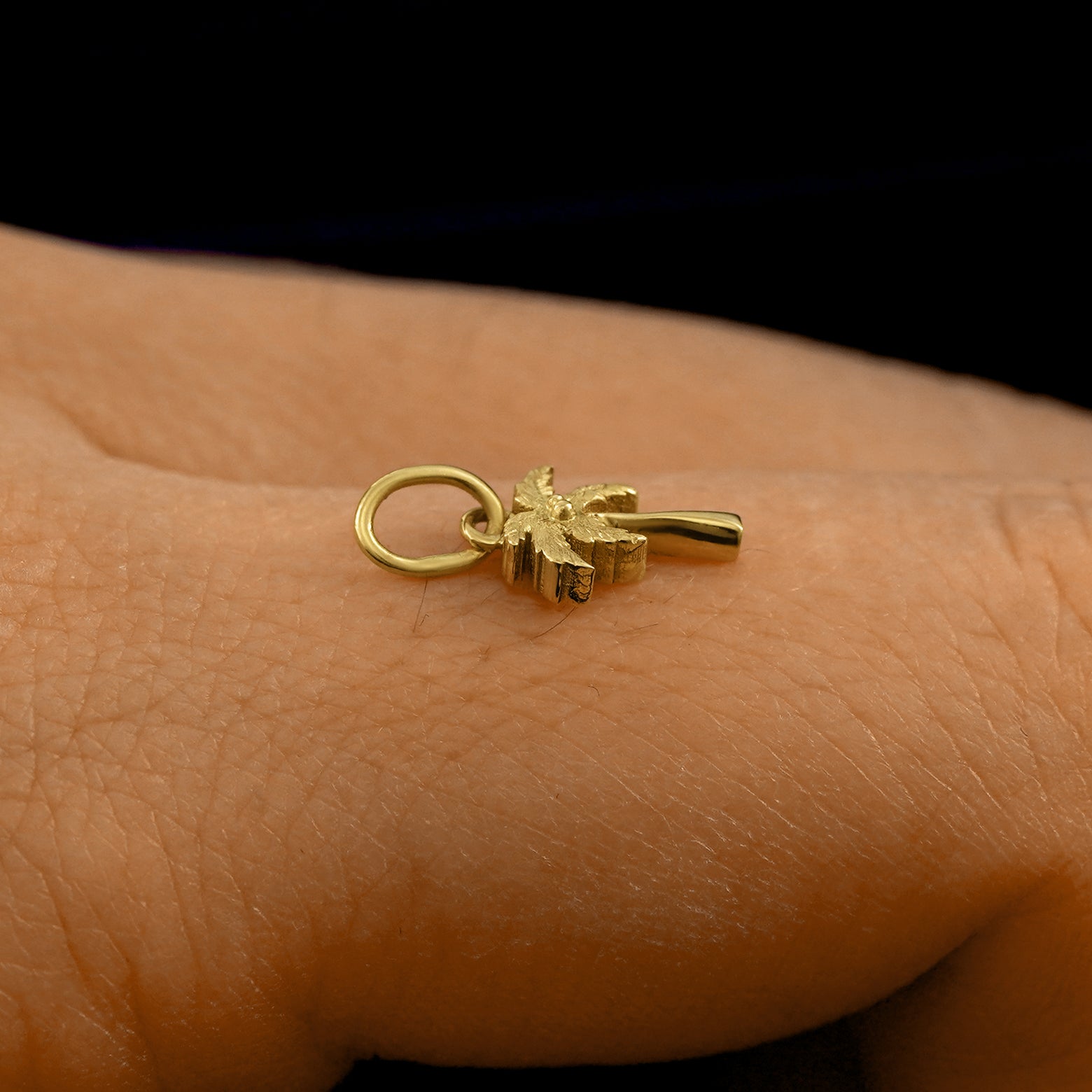 Side view of a 14k solid gold Palm Tree Charm on a model's finger to show the details and thickness of the charm