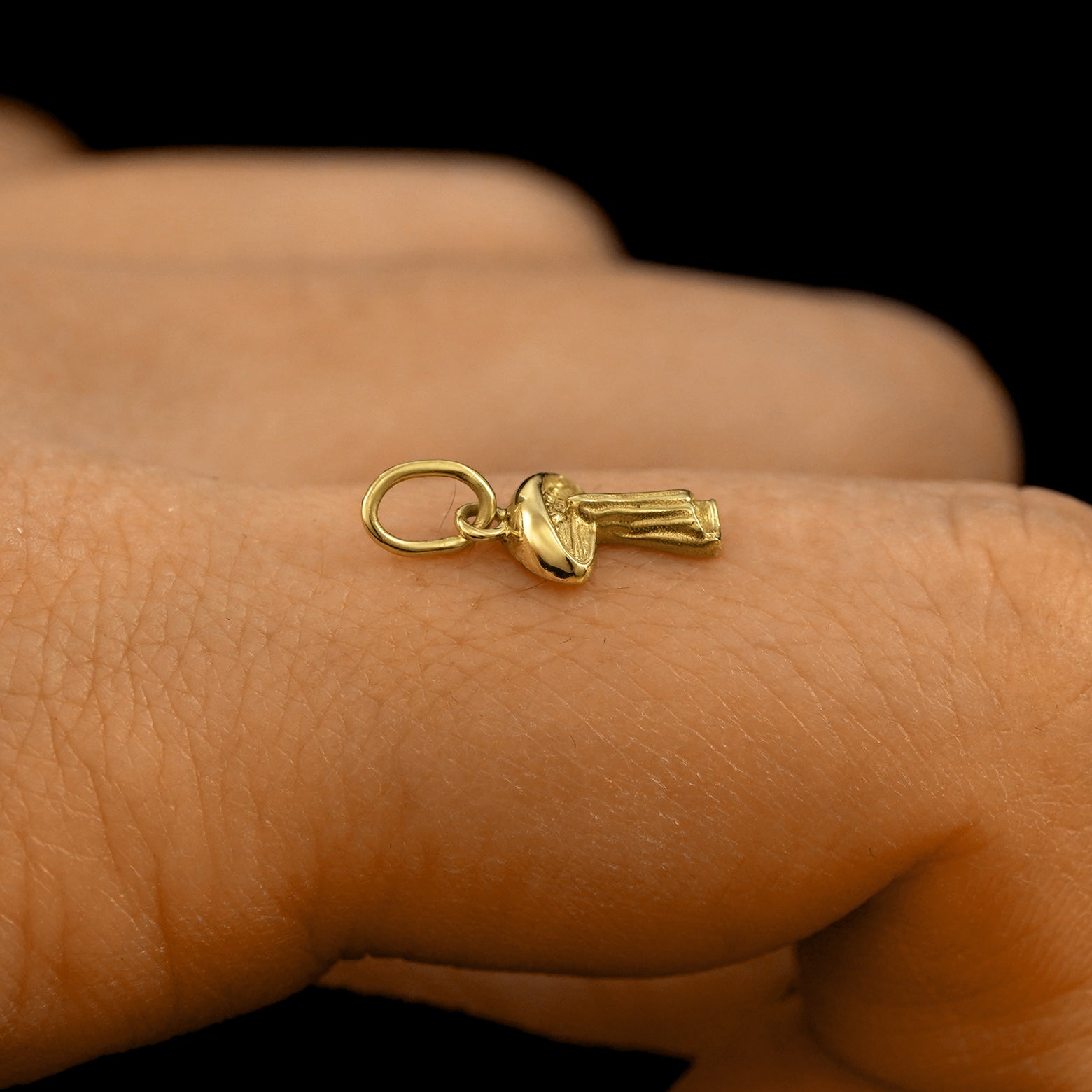 Side view of a 14k solid gold Mushroom Charm on a model's finger to show the details and thickness of the charm