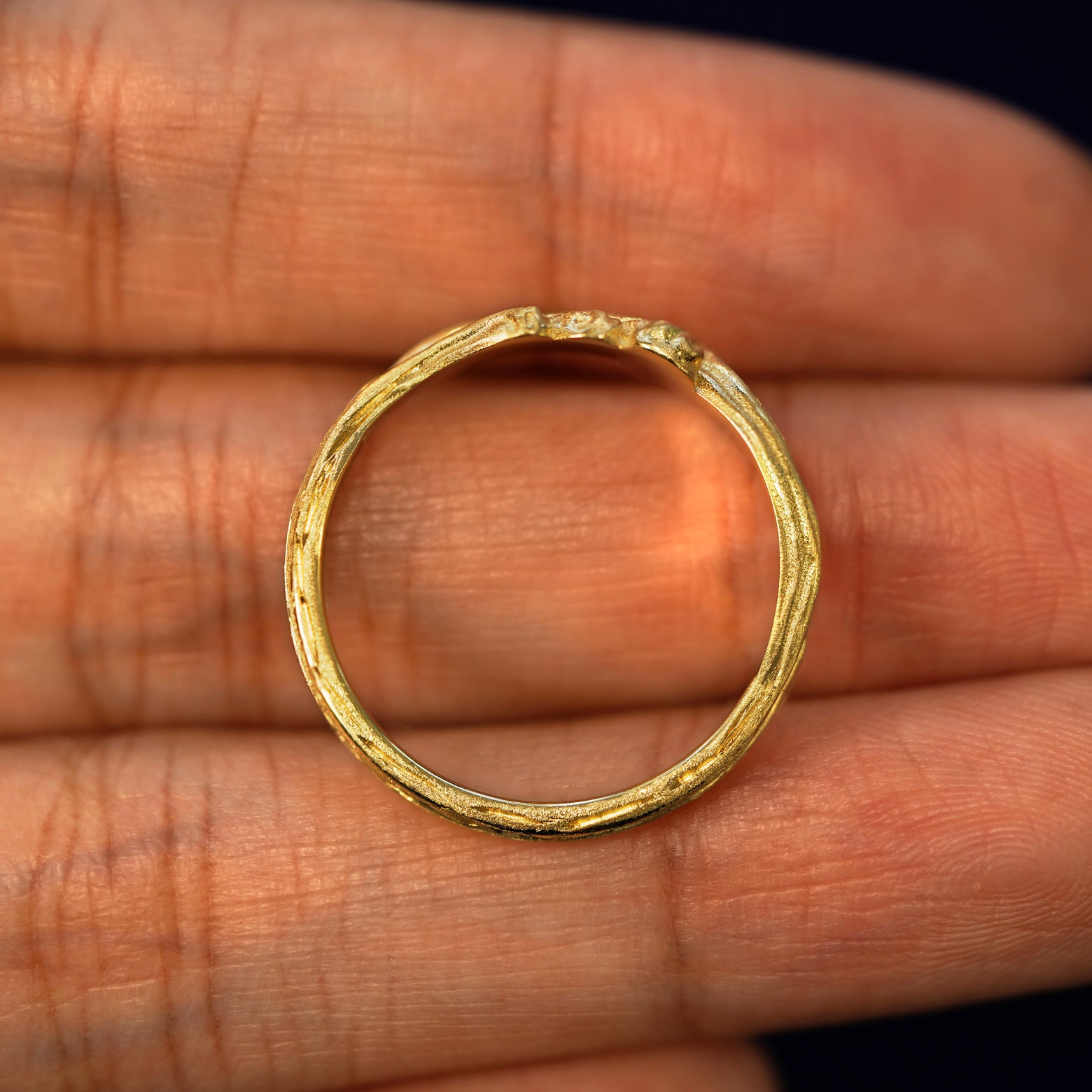A yellow gold Crashing Waves Band in a model's hand showing the thickness of the band