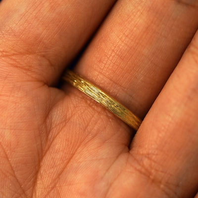 Close up view of the underside of a model's hand  wearing a 14k yellow gold Crashing Waves Band to show the continued design