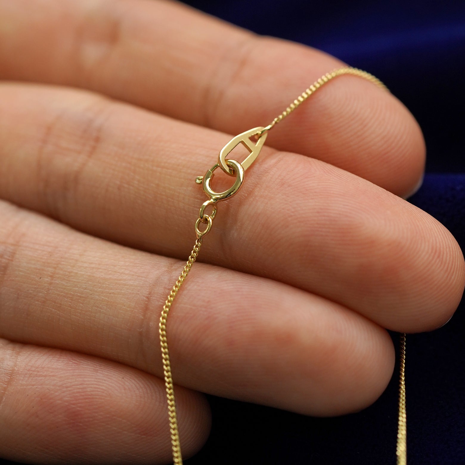 A model holding a moon necklace to show the lobster claw clasp on the essential chain