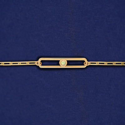 A yellow gold elongated open oval link with a single bezel set Opal inside on a 14k gold Butch chain bracelet