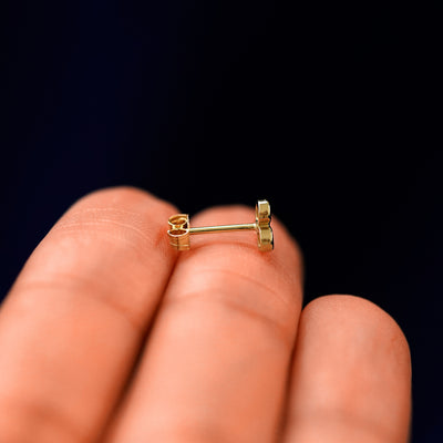 Side view of a Diamond Trio Earring with a standard pushback backing sitting on a model's fingertips