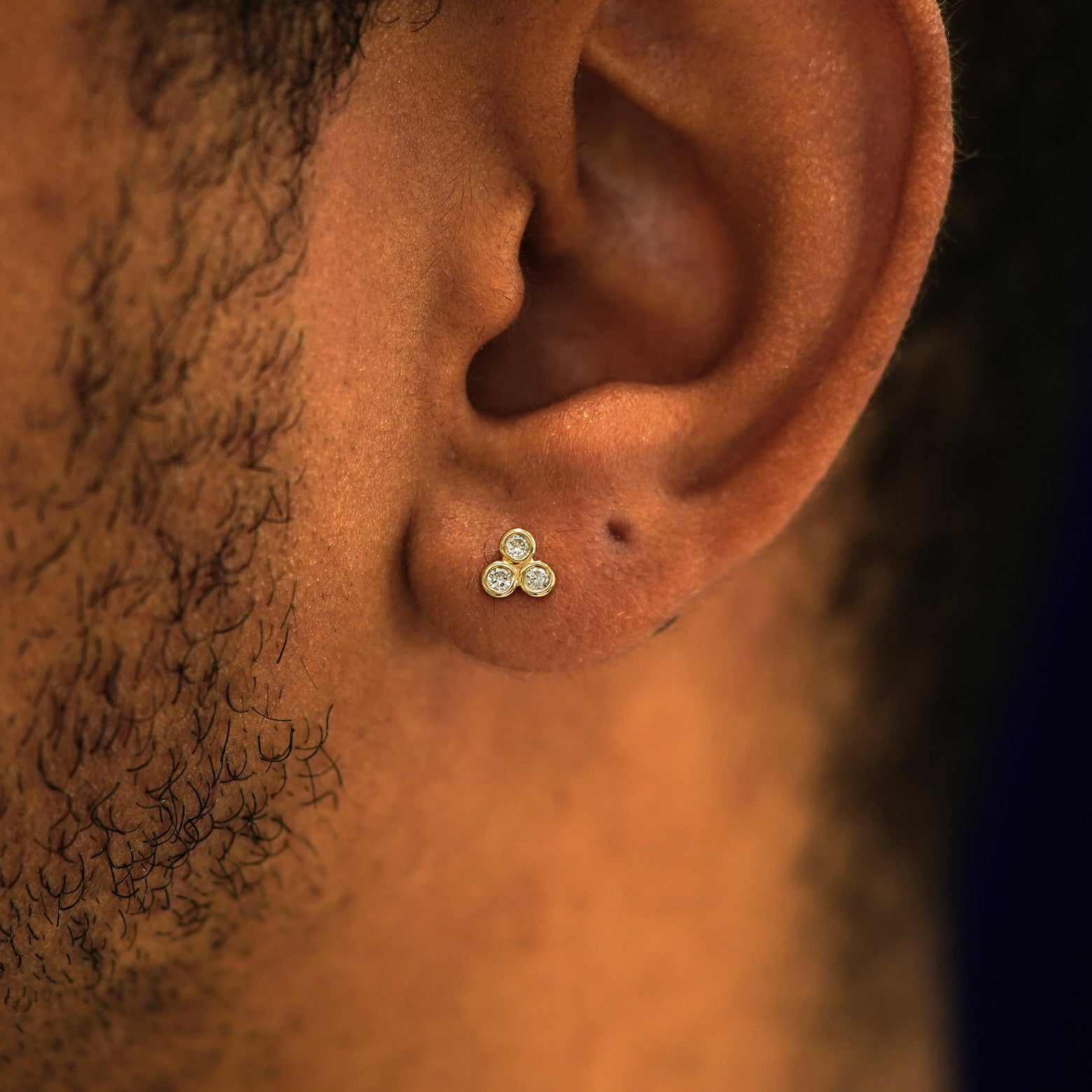 A model's ear wearing a 14k yellow gold Diamond Trio Earring