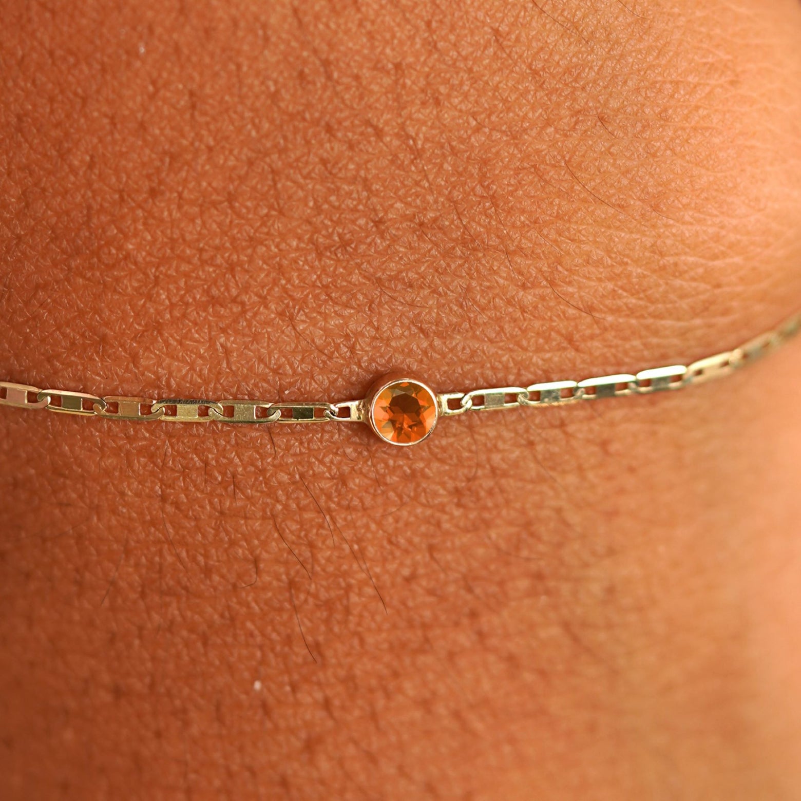 Close up view of a models wrist wearing 14k yellow gold Fire Opal Bracelet