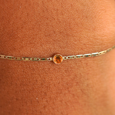 Close up view of a models wrist wearing 14k yellow gold Fire Opal Bracelet