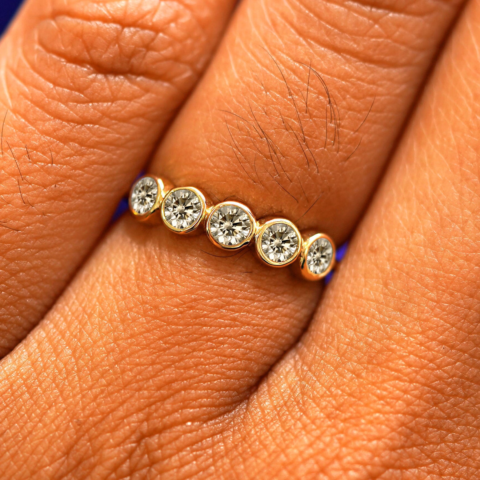 Close up view of a model's fingers wearing a 14k yellow gold Five Diamond Ring with champagne diamonds