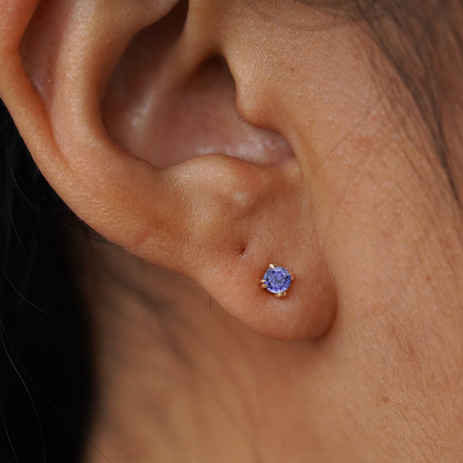 Close up view of a model's ear wearing a yellow gold Tanzanite Flat Back Earring