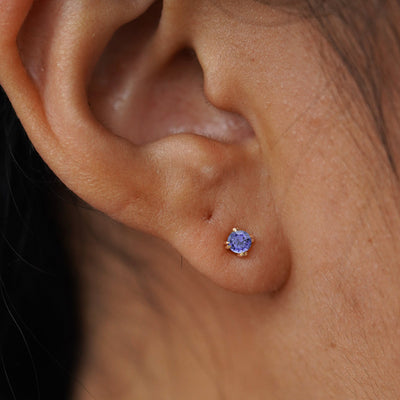 Close up view of a model's ear wearing a yellow gold Tanzanite Flat Back Earring