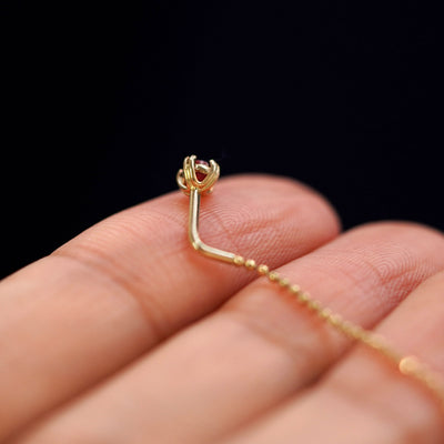A yellow gold garnet Gemstone Ear Threader Earring laying facedown on a model's fingers to show the underside view