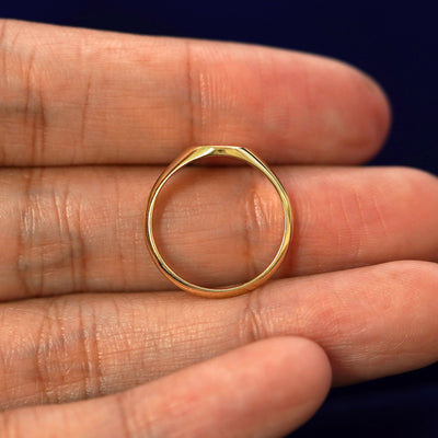 A yellow gold sapphire Gemstone Signet Ring in a model's hand showing the thickness of the band